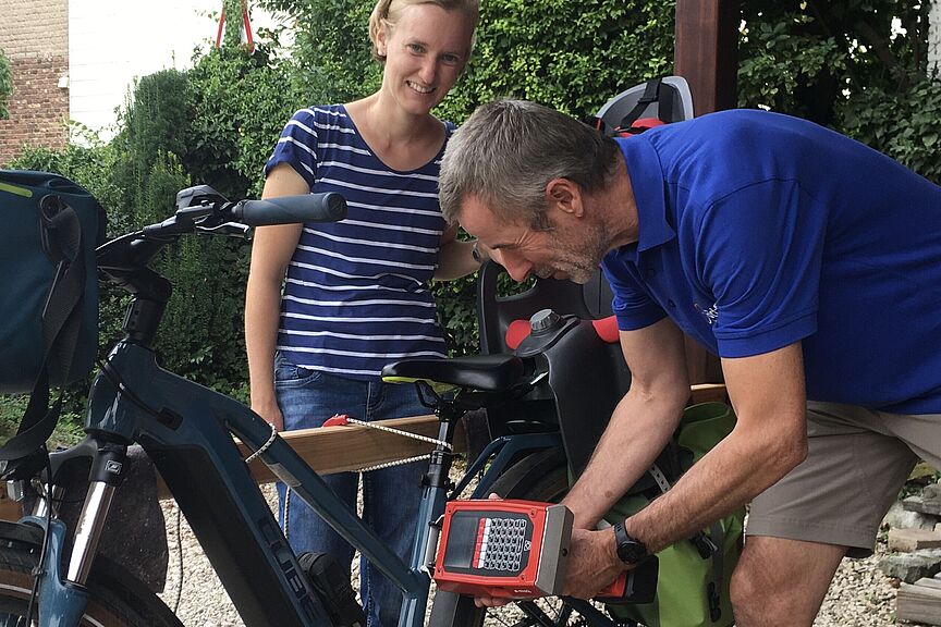 Foto Codierung E-Bike Das Foto zeigt Jörg Landmann vom ADFC Wachtberg beim Einstanzen des Codes in den rahmen eines E-Bikes. Die Besitzerin des Fahrrads schaut erfreut zu.