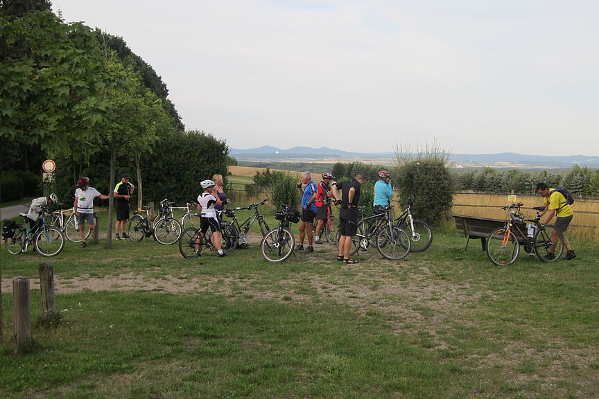 Pause Tour auf das Siebengebirge Das Bild zeigt eine Radlergruppe während einer Rast, im Hintergrund ein weiter Blick auf das Siebengebirge