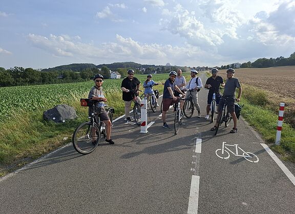 Das Foto zeigt die genannte Gruppe aus Politik, Verwaltung und ADFC bei einem Halt an der zerstörten Schranke am Berkumer Weg