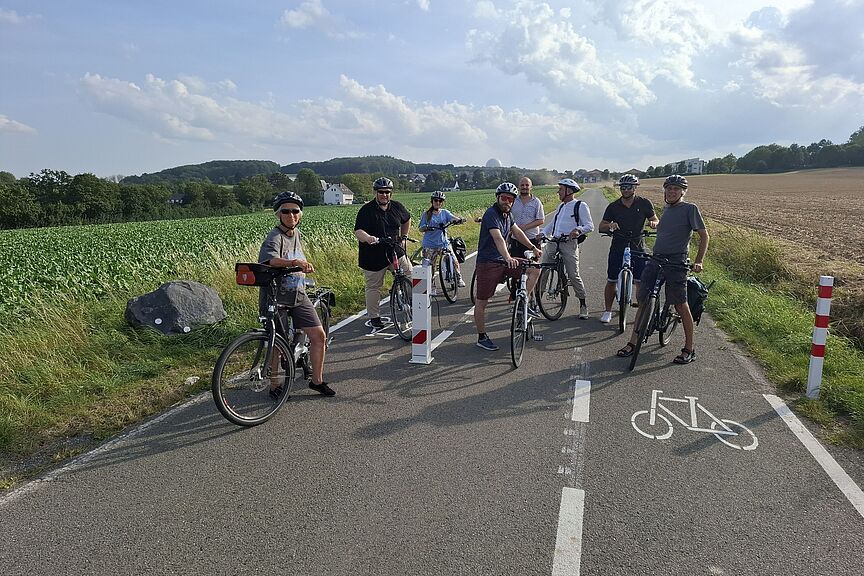 Politiktour Schranke Berkumer Weg Das Foto zeigt die genannte Gruppe aus Politik, Verwaltung und ADFC bei einem Halt an der zerstörten Schranke am Berkumer Weg