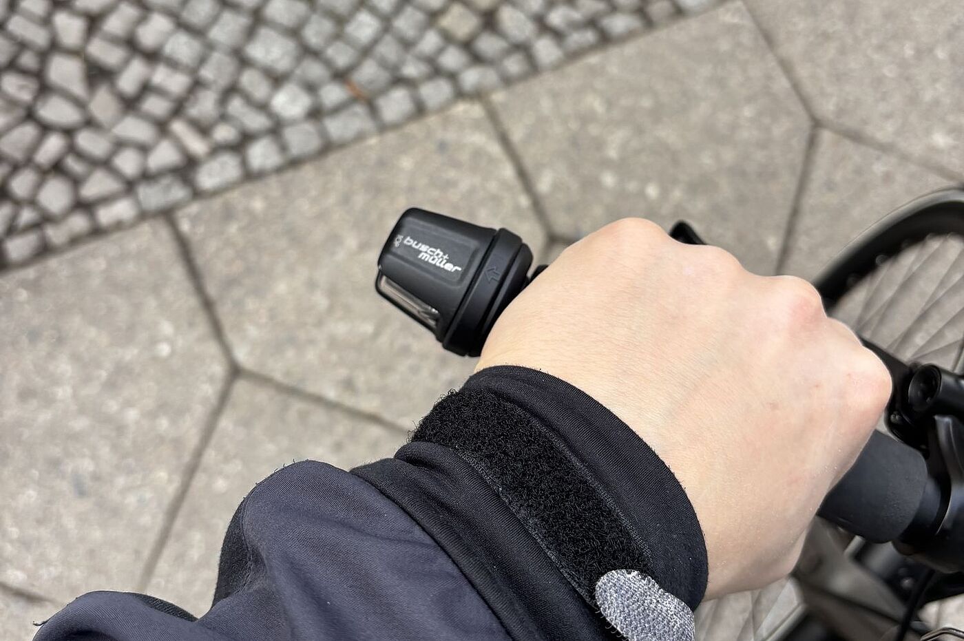 Hand am Blinker Eine Hand am Fahrradgriff, daneben ein Fahrradblinker.